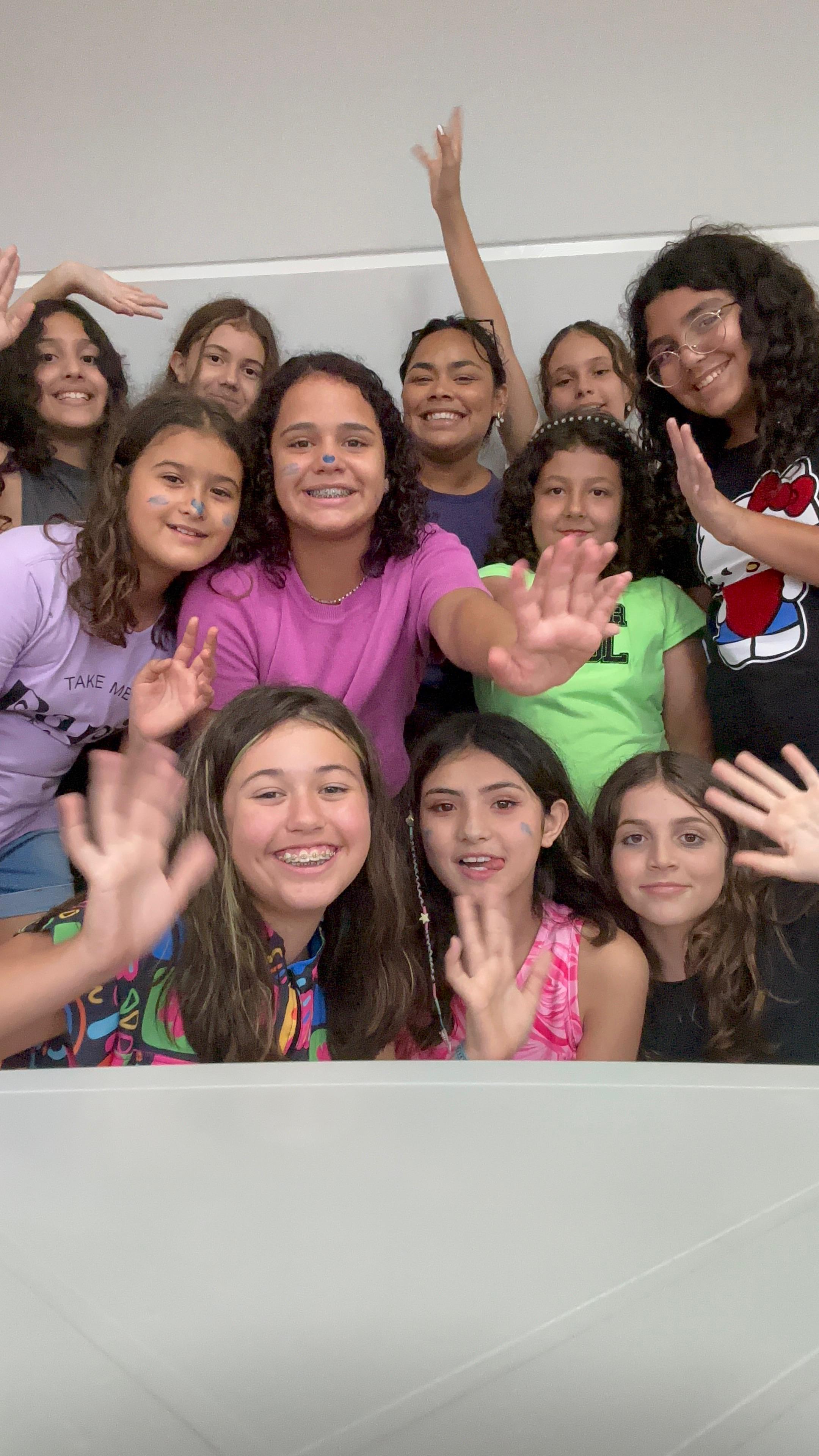 Grupo de crianças animadas sorrindo e acenando para a câmera